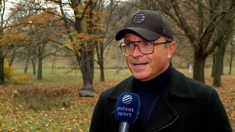 Bożydar Iwanow w czapce z daszkiem i okularach stoi na tle jesiennego parku i udziela wywiadu z mikrofonem Polsat Sport.