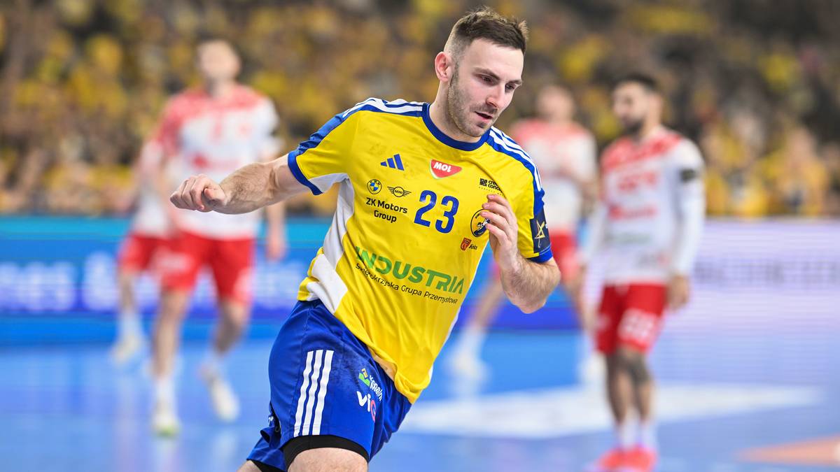 Piłkarz ręczny w ż&oacute;łtej koszulce z numerem 23 biegnie po boisku.