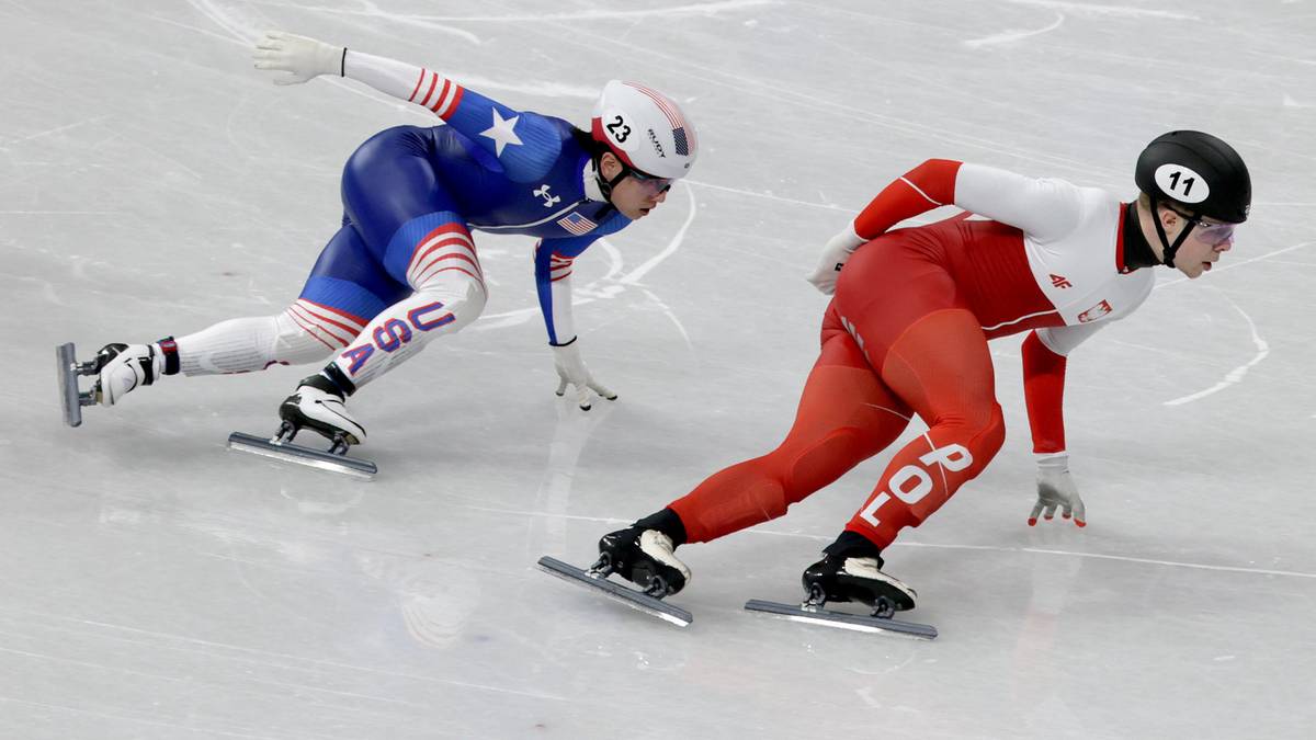 Dw&oacute;ch łyżwiarzy szybkich na lodzie. Jeden w stroju USA, drugi w stroju Polski.