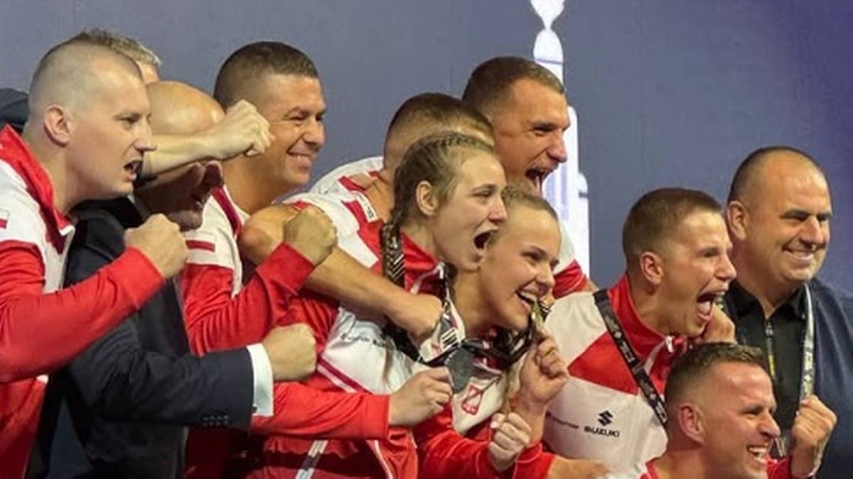 Grupa polskich bokserów w strojach sportowych z medalami na szyjach, świętująca sukces.