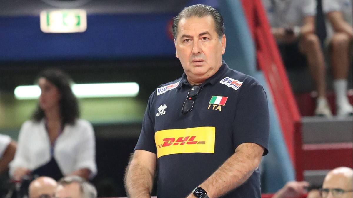 Angelo Lorenzetti, trener reprezentacji Włoch w siatk&oacute;wce mężczyzn, w ciemnej koszulce z ż&oacute;łtym logo DHL i włoską flagą na kołnierzyku.