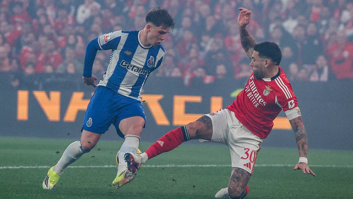 Dw&oacute;ch piłkarzy FC Porto i Benfiki rywalizuje o piłkę na boisku podczas meczu.