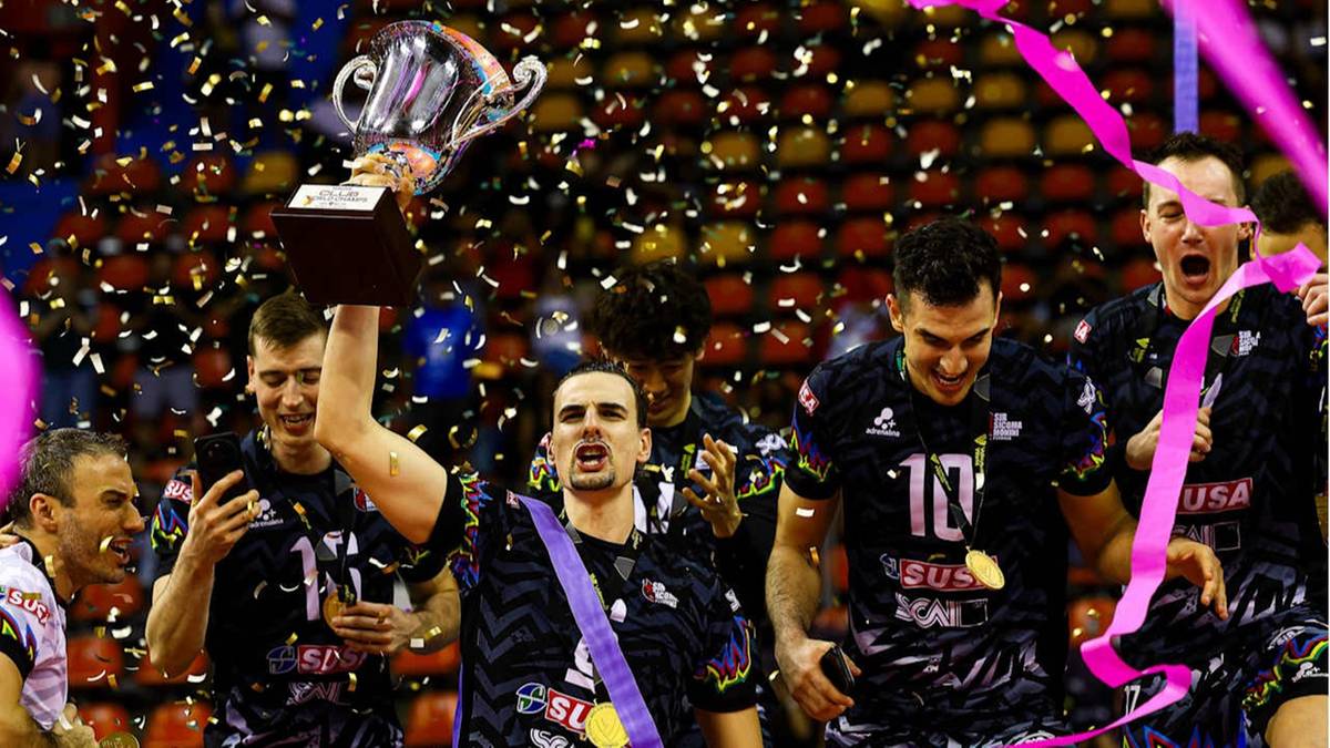 Drużyna siatkarska świętuje zwycięstwo, unosząc puchar i celebrując w otoczeniu konfetti i wstążek.