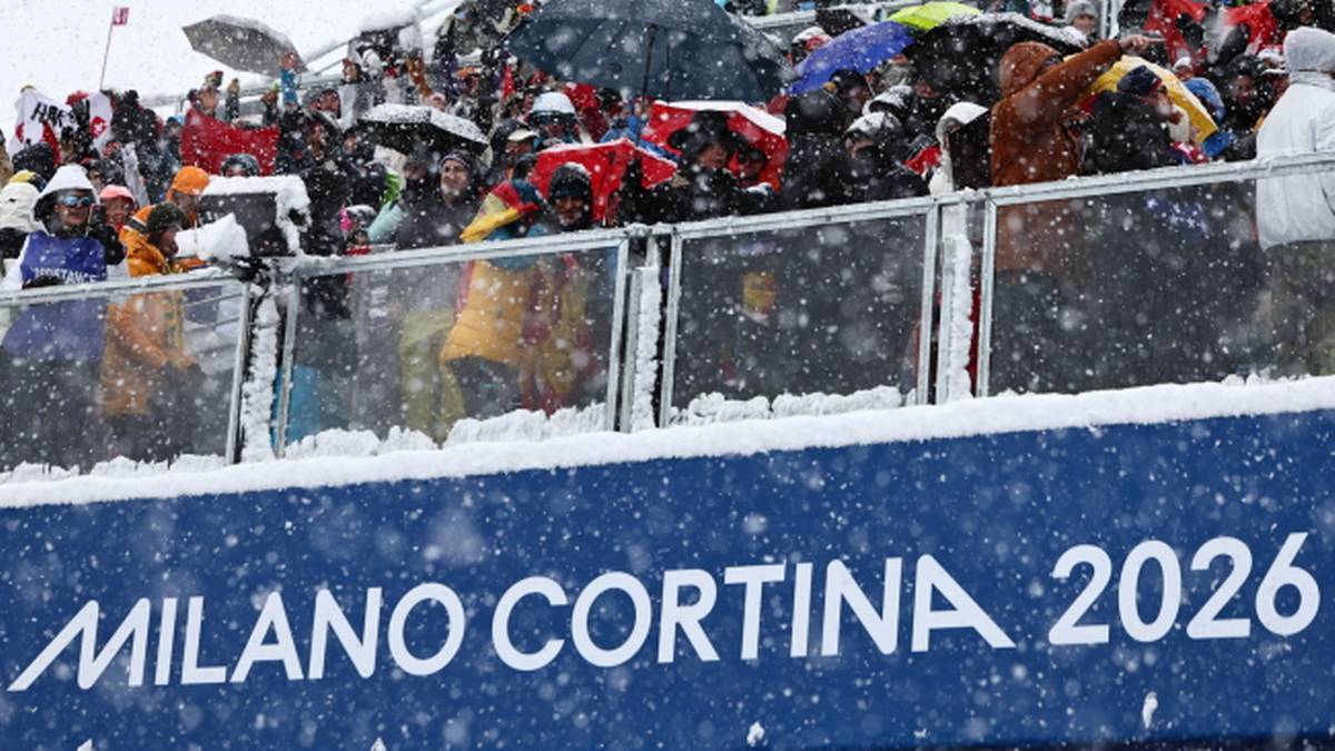 Widzowie na trybunach podczas zimowych zawod&oacute;w sportowych z banerem "MILANO CORTINA 2026".