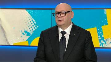 Mężczyzna w garniturze i okularach patrzy na rozm&oacute;wcę.