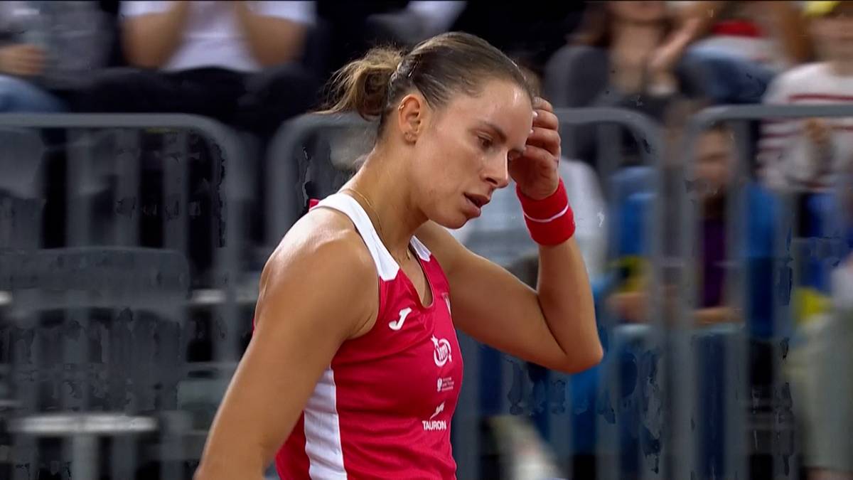 Magda Linette podczas meczu tenisowego, dotykająca czoła.