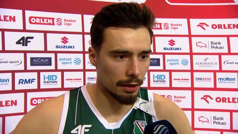 Zbliżenie na twarz Andrzeja Pluty, koszykarza w zielono-białej koszulce. Mężczyzna ma zarost i spogląda w bok z poważnym wyrazem twarzy.