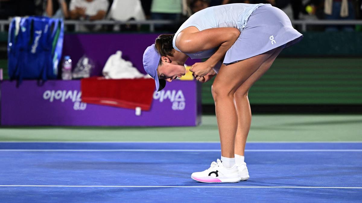 Tenisistka Iga Świątek pochylona w geście podziękowania lub radości na korcie tenisowym.