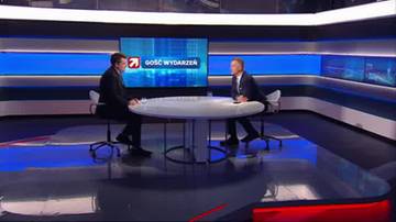 Dw&oacute;ch mężczyzn siedzi naprzeciwko siebie przy owalnym stole w studiu telewizyjnym. Na ekranie za nimi widnieje logo programu "Gość Wydarzeń".