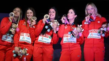 Pięć młodych kobiet w czerwonych dresach z medalami na szyjach i pluszowymi zabawkami w rękach.