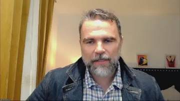 Zbliżenie na twarz mężczyzny z brodą, ubranego w koszulę w kratę i kurtkę jeansową.