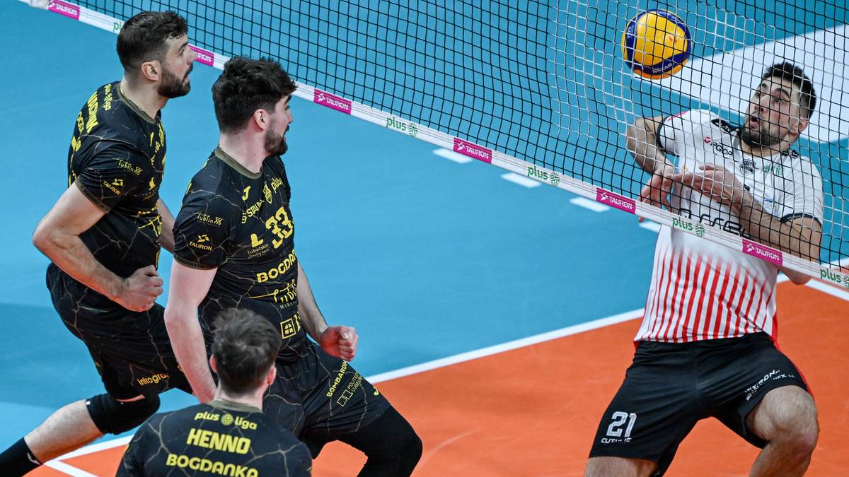 Siatkarze w akcji podczas meczu, jeden z nich odbija piłkę nad siatką.