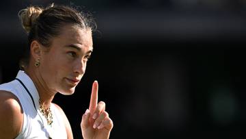 Aryna Sabalenka, tenisistka, z uniesionym palcem wskazującym, skupiona na tle.
