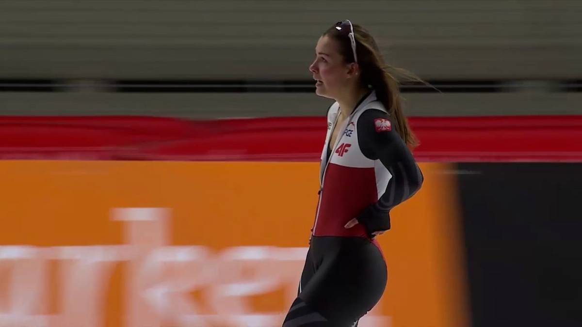 Łyżwiarka szybka w biało-czerwonym stroju podczas biegu.