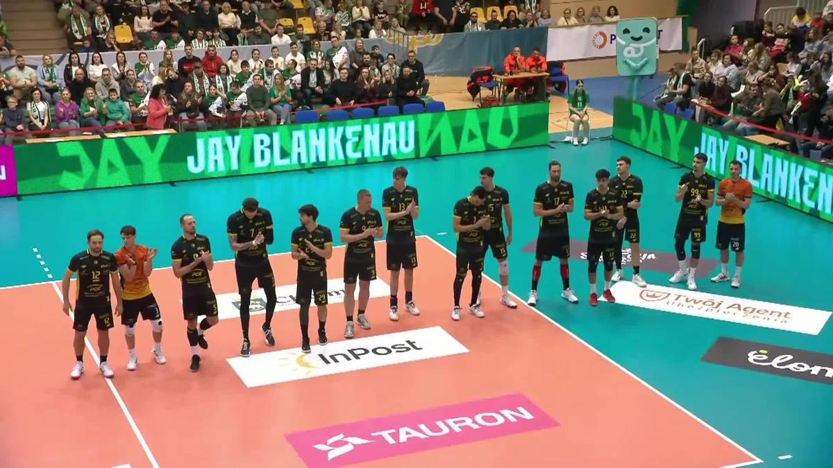 Drużyna siatkarzy w czarnych strojach na boisku.