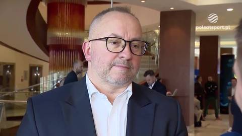 Grzegorz Bachański, mężczyzna w okularach i garniturze, udziela wywiadu.