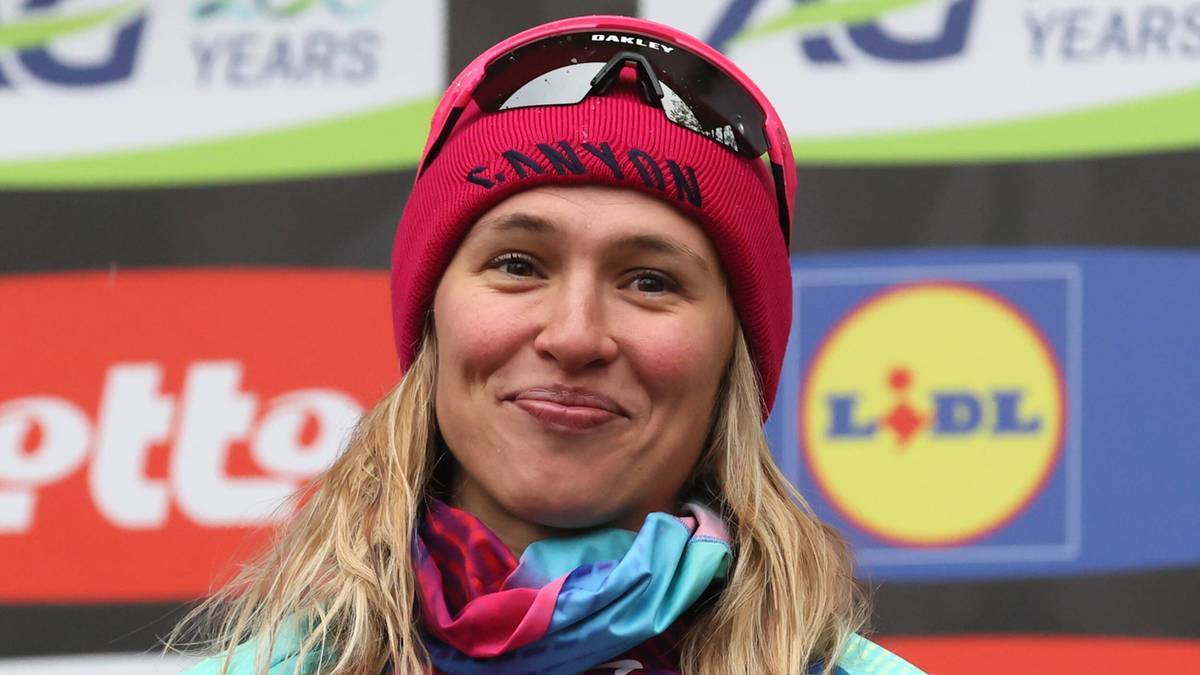 Kobieta w czapce i okularach sportowych, uśmiechnięta.