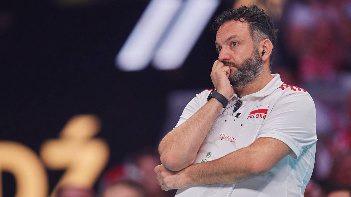 Stefano Lavarini, trener reprezentacji Polski siatkówki mężczyzn, w białej koszulce, zamyślony, opierający dłoń o brodę.