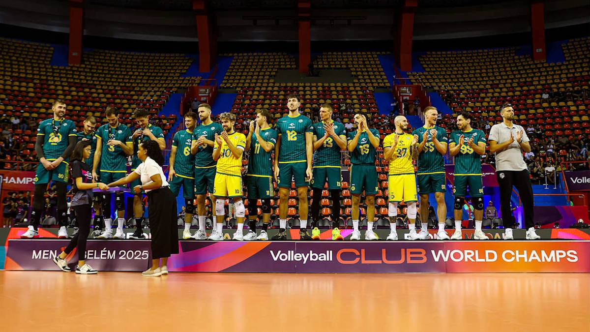 Drużyna siatkarzy w zielonych strojach stoi na podium z pucharem.