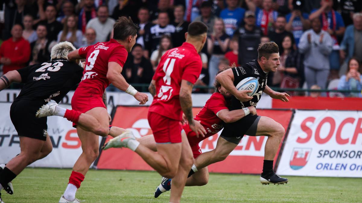 Gracz rugby w akcji, pr&oacute;bujący uciec przed obroną przeciwnika.