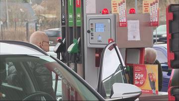 Widok na dystrybutory paliwa na stacji benzynowej, z widocznym ekranem pokazującym ceny.