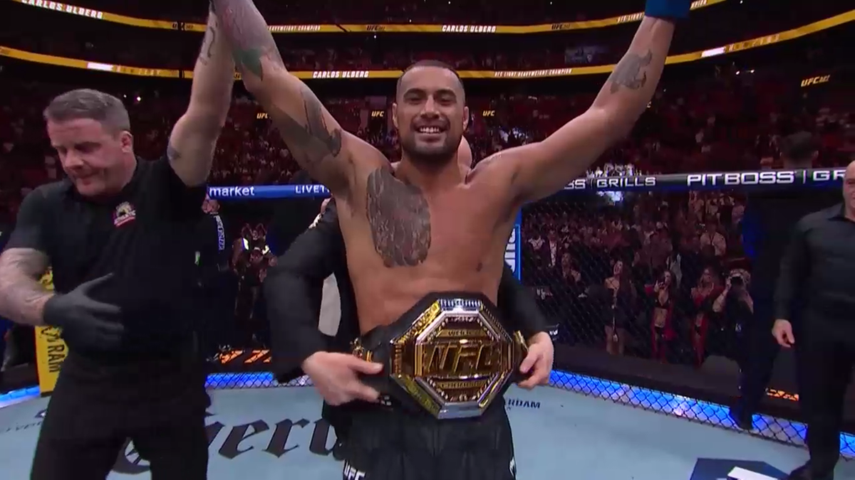 Carlos Ulberg wznosi ręce w geście zwycięstwa, trzymając pas mistrzowski UFC.