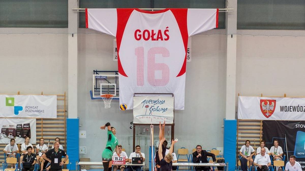Wielka biało-czerwona koszulka z napisem "GOŁAŚ" i numerem "16" podwieszona pod sufitem hali sportowej.