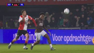 Dwóch piłkarzy rywalizuje o piłkę podczas meczu piłki nożnej. Jeden zawodnik w czerwono-białej koszulce i drugi w brązowej koszulce biegną po boisku. Piłka znajduje się w powietrzu nad nimi.