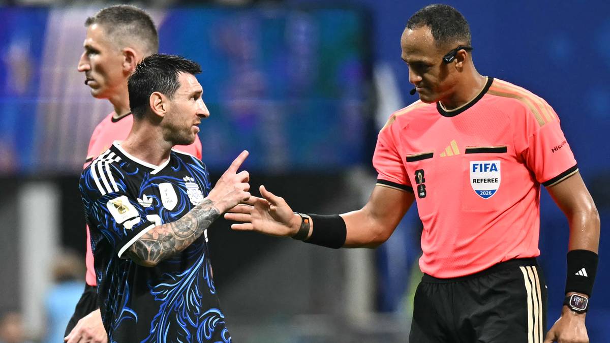 Sędzia w r&oacute;żowej koszulce z opaską FIFA rozmawia z piłkarzem Leo Messim w czarno-niebieskiej koszulce.