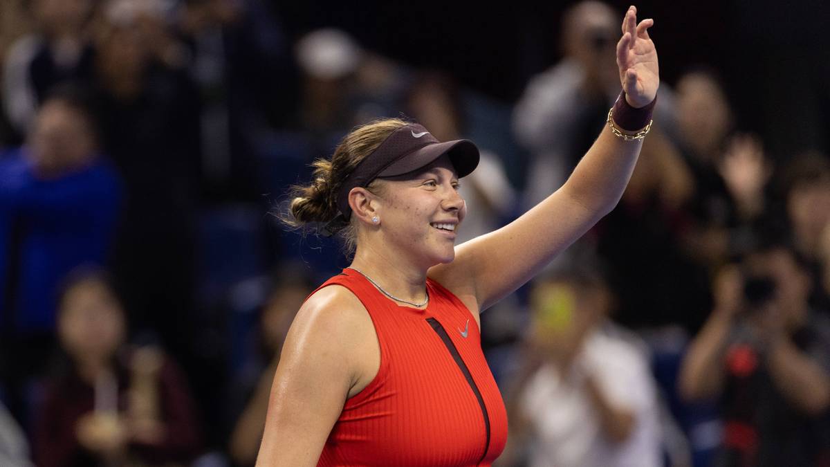 Amanda Anisimova w czerwonym stroju sportowym świętuje zwycięstwo, unosząc rękę