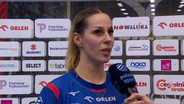 Kobieta w niebieskiej koszulce sportowej z logo "ORLEN" m&oacute;wi do mikrofonu. W tle widoczne są białe tablice z logo sponsor&oacute;w.