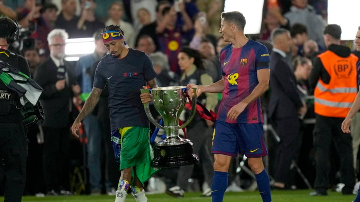 Dw&oacute;ch piłkarzy w strojach Barcelony idzie z pucharem, jeden z nich to Robert Lewandowski.