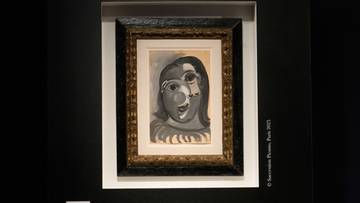 Obraz zatytułowany "Głowa kobiety" autorstwa Pabla Picassa, przedstawiający twarz kobiety w stylu kubistycznym, wykonany gwaszem w odcieniach szarości i czerni.