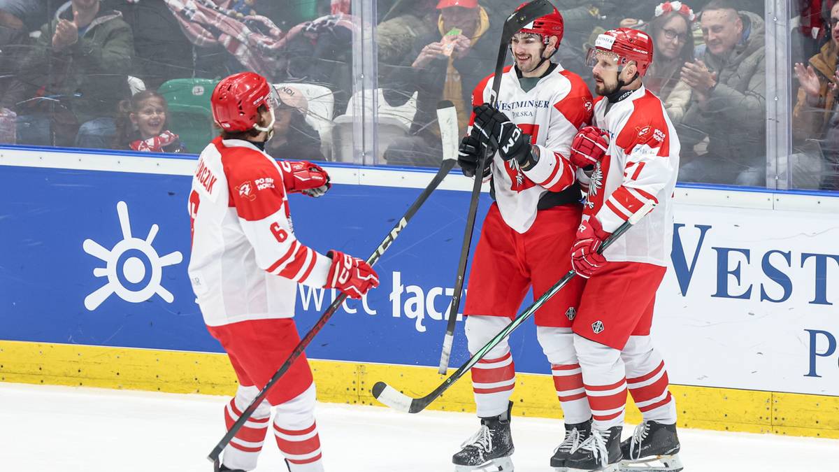 Trzech zawodników hokeja w białych strojach świętuje na lodzie.