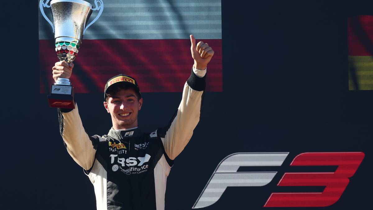 Młody kierowca wyścigowy Roman Biliński z pucharem i uniesionym kciukiem na podium F3