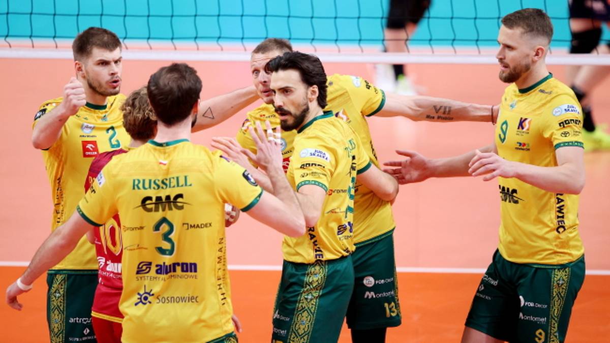 Grupa siatkarzy w żółtych koszulkach świętuje na boisku.