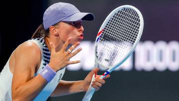 Iga Świątek dmucha na rakietę tenisową, przygotowując się do zagrania.