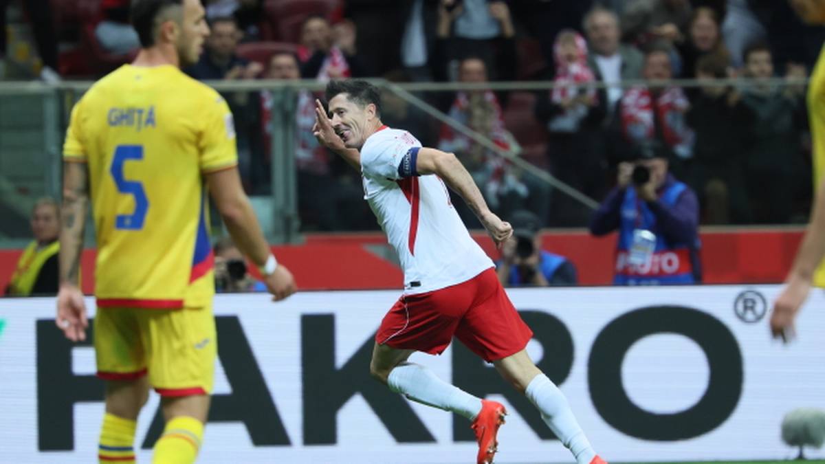 Polski piłkarz celebruje zdobycie bramki na boisku piłkarskim, w tle widoczny zawodnik w żółtym stroju