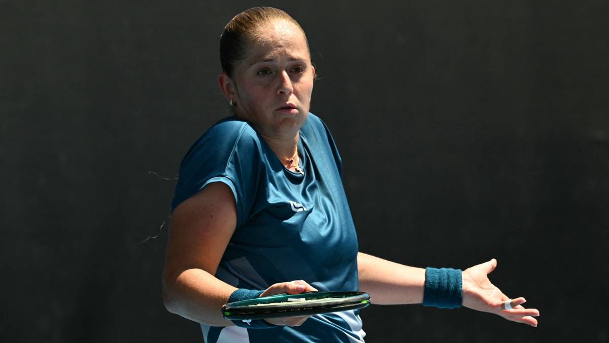 Tenisistka Laura Siegemund w niebieskiej bluzce i białej sp&oacute;dniczce, trzymająca rakietę, z wyrazem zaskoczenia na twarzy.