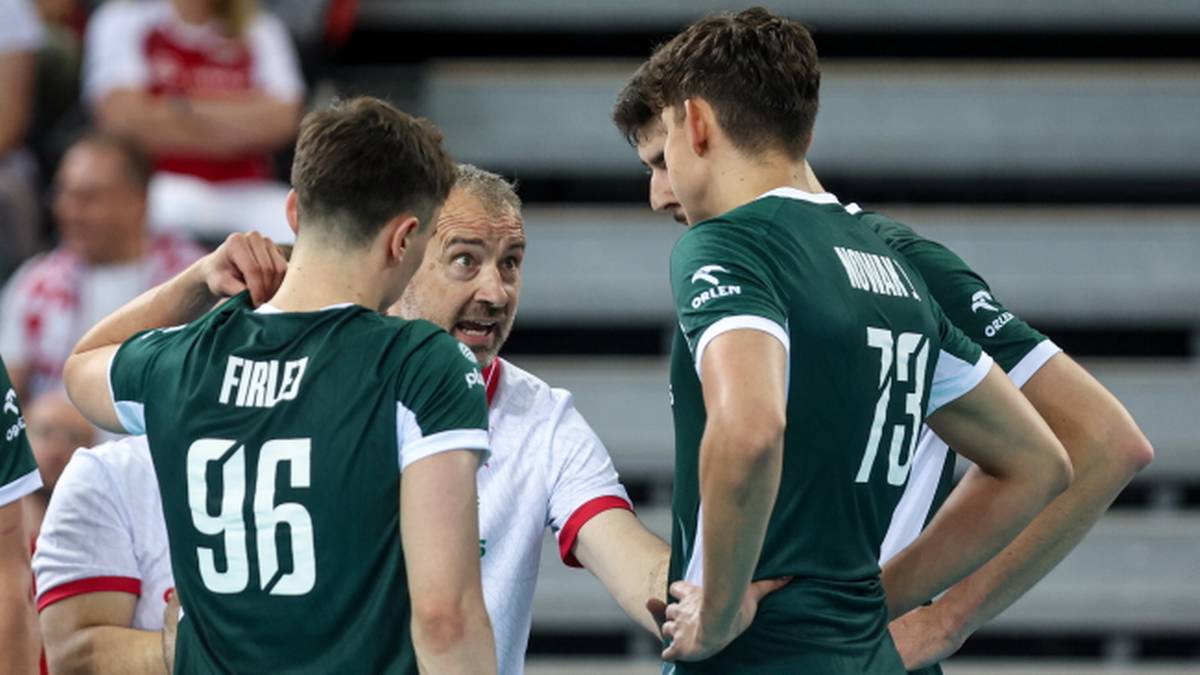 Trener siatkówki rozmawia z dwoma zawodnikami w zielonych koszulkach z numerami 96 i 73.