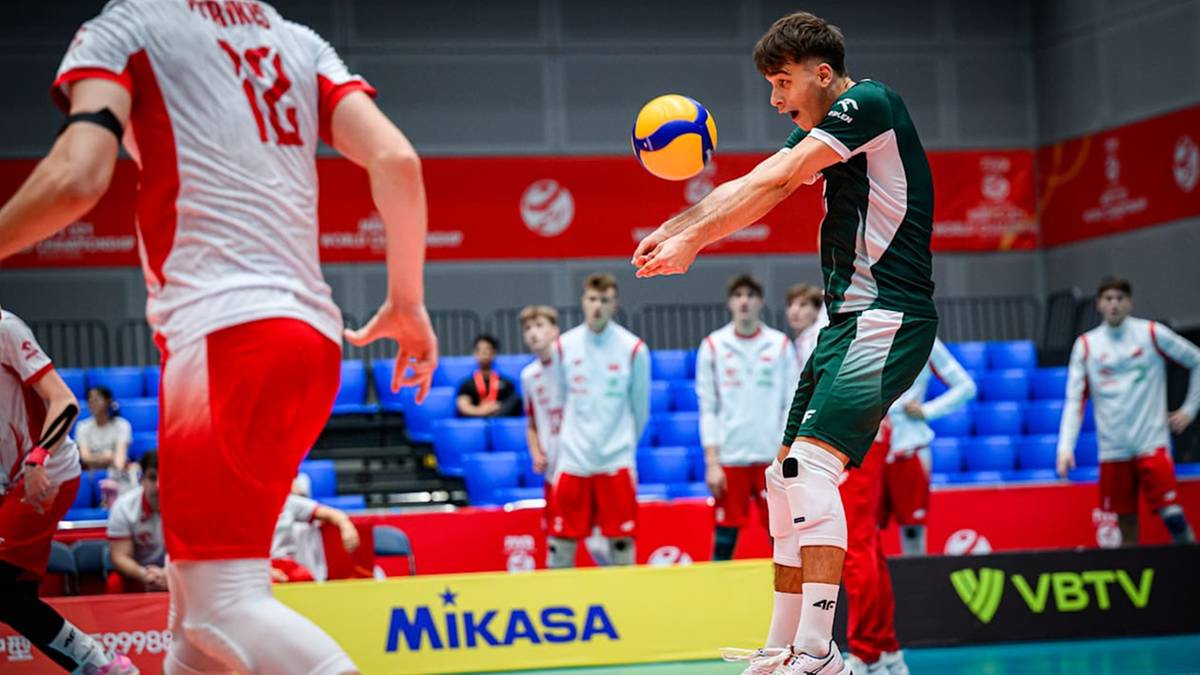 Gracz w zielonej koszulce odbija piłkę do siatkówki na boisku, w tle inni zawodnicy i publiczność.