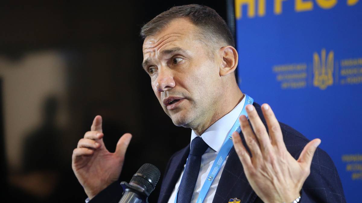 Andrij Szewczenko, mężczyzna w garniturze, przemawia do mikrofonu, gestykulując rękami.