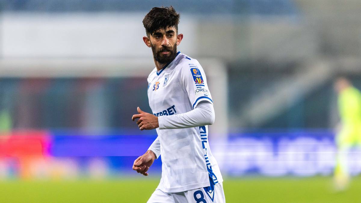 Piłkarz w białej koszulce Lecha Poznań z numerem 8 na boisku piłkarskim