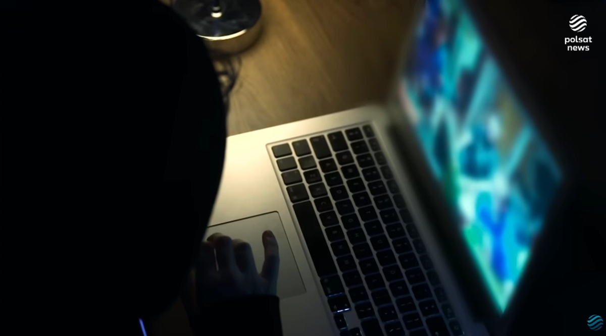 Osoba korzystająca z laptopa w ciemności, na ekranie widoczny podgląd z wielu kamer.