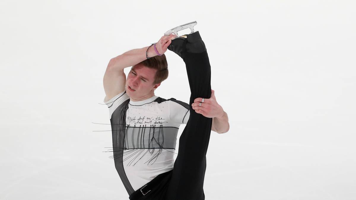 Łyżwiarz figurowy wykonujący akrobatyczną pozycję na lodowisku.