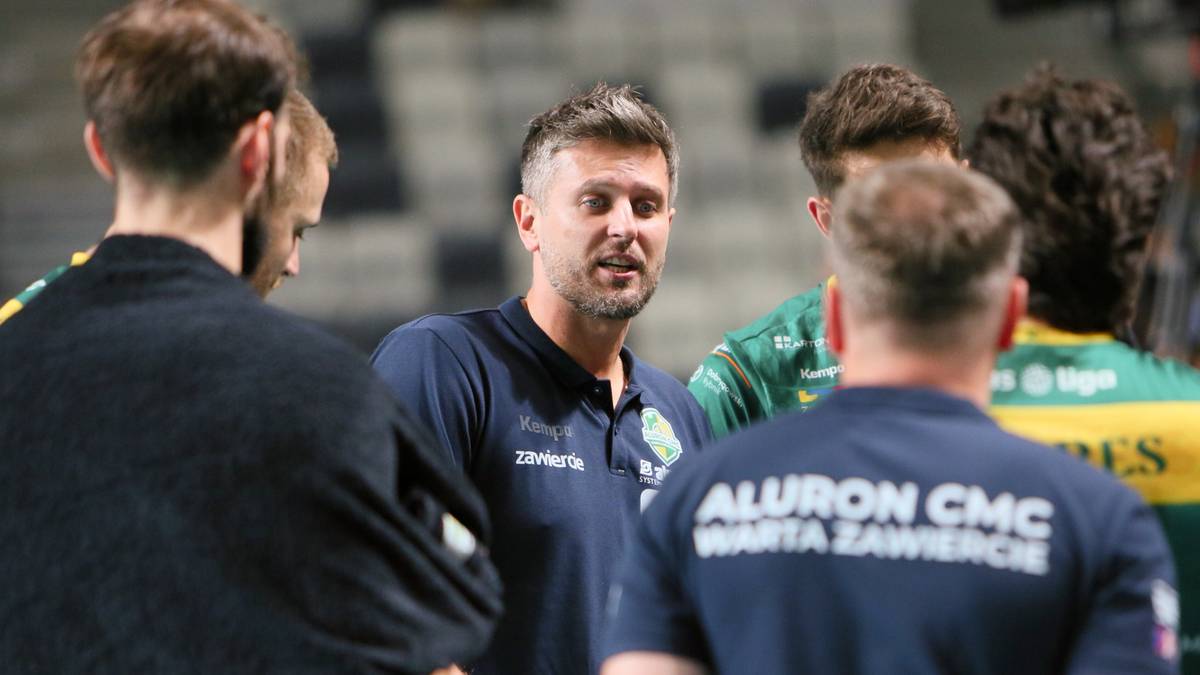 Trener siatk&oacute;wki w niebieskiej koszulce drużyny "ALURON CMC WARTA ZAWIERCIE" rozmawia z zawodnikami.