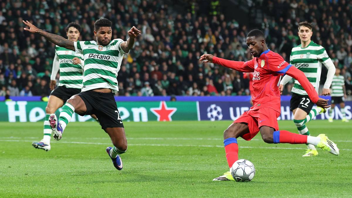 Dw&oacute;ch piłkarzy na boisku, jeden w czerwonym stroju pr&oacute;buje strzelić gola, drugi w zielono-białym stroju pr&oacute;buje go zablokować. W tle publiczność.