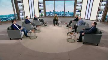 Grupa os&oacute;b siedzących w okręgu w studio telewizyjnym, dyskutujących.