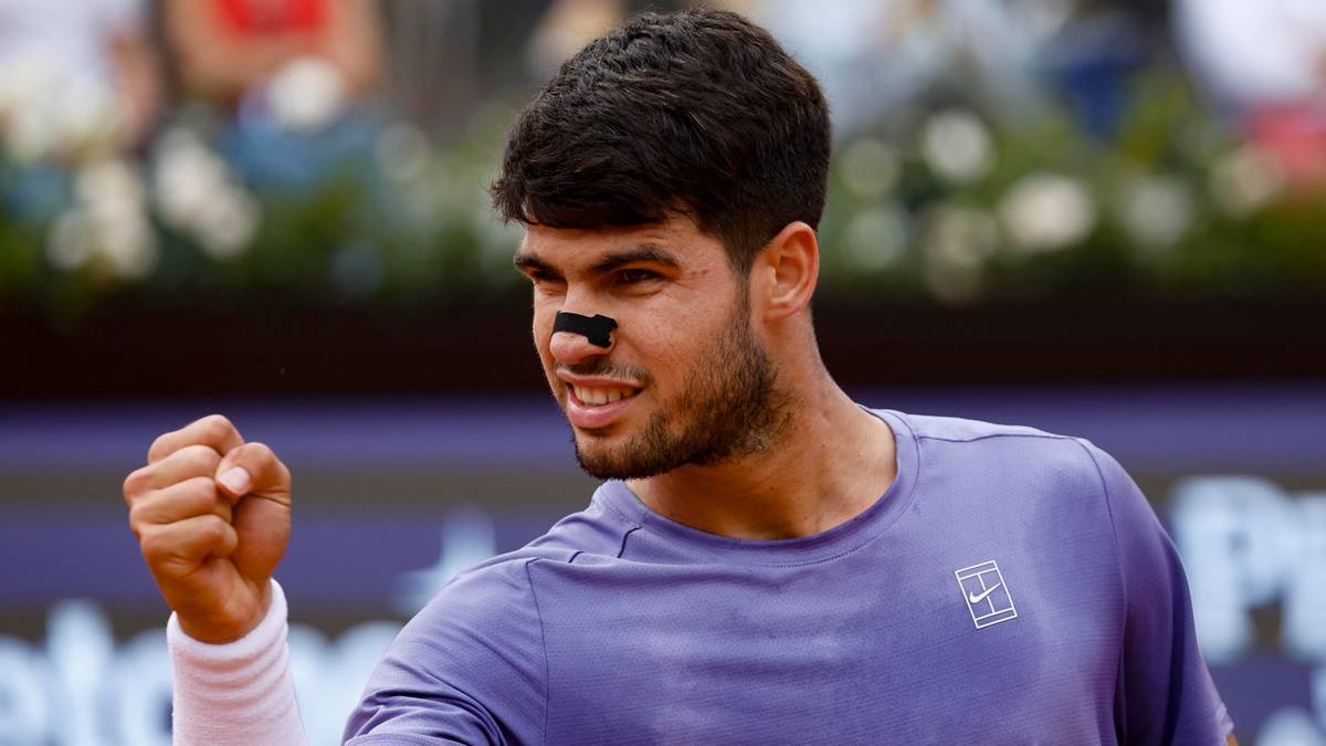 Carlos Alcaraz, tenisista, radośnie zaciska pięść w geście triumfu podczas meczu na kortach ziemnych.