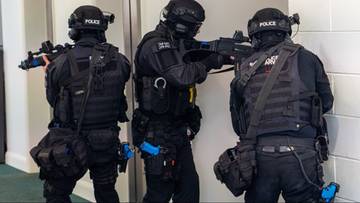 Trzech policjant&oacute;w w pełnym rynsztunku taktycznym i hełmach, trzymających broń.